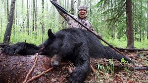 hombre cazador victorioso con cuerpo de oso muerto a sus pies