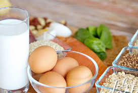 Vaso de leche y envase con huevos, en mesa con diferentes tipos de cereales